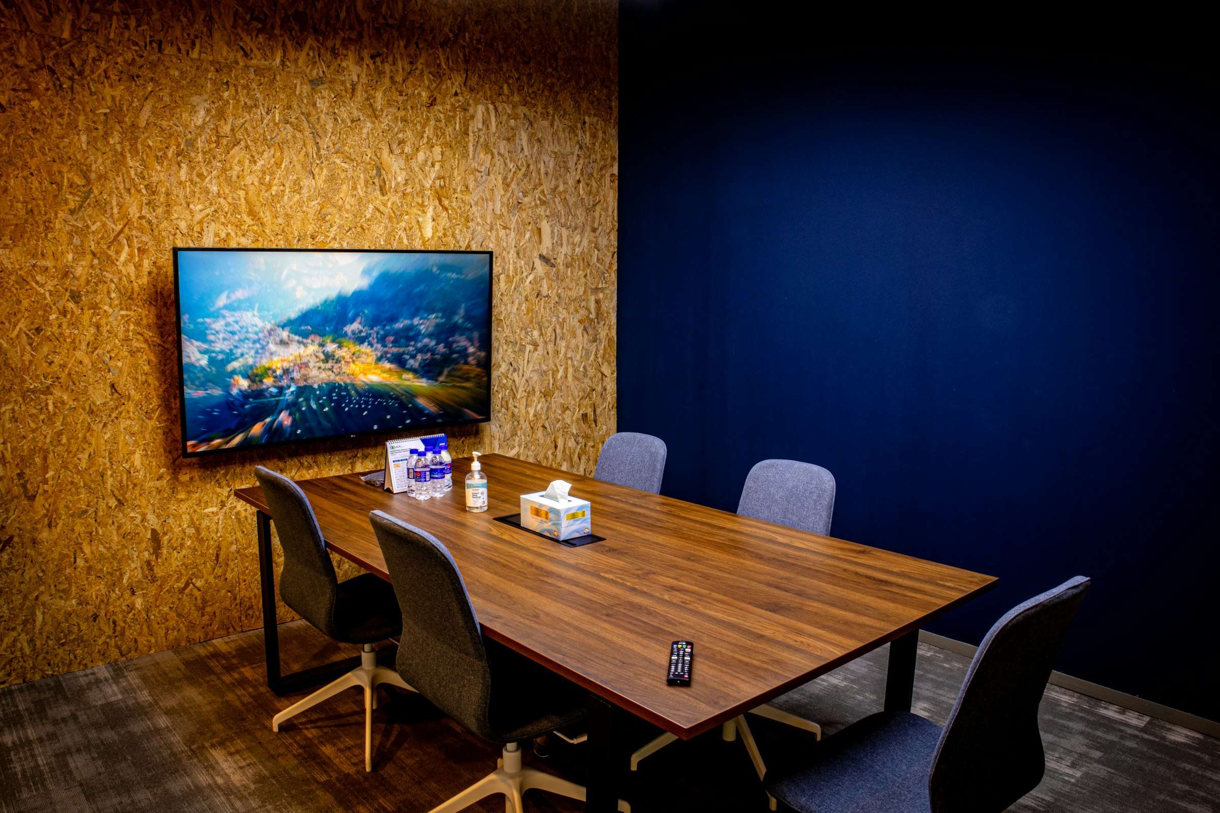 Voorbeeldfoto: een kleine vergaderruimte met een wandscherm tegen een marineblauwe muur en een notenhouten tafel.